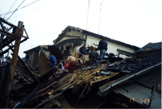 1995年1月17日午前7時27分頃、神戸市灘区にて撮影。近隣の若い男性らがグループを作り、全壊した住宅から救出を行う様子。